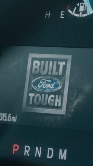 The dashboard of a Ford truck, “Built Ford Tough” between the gauges.