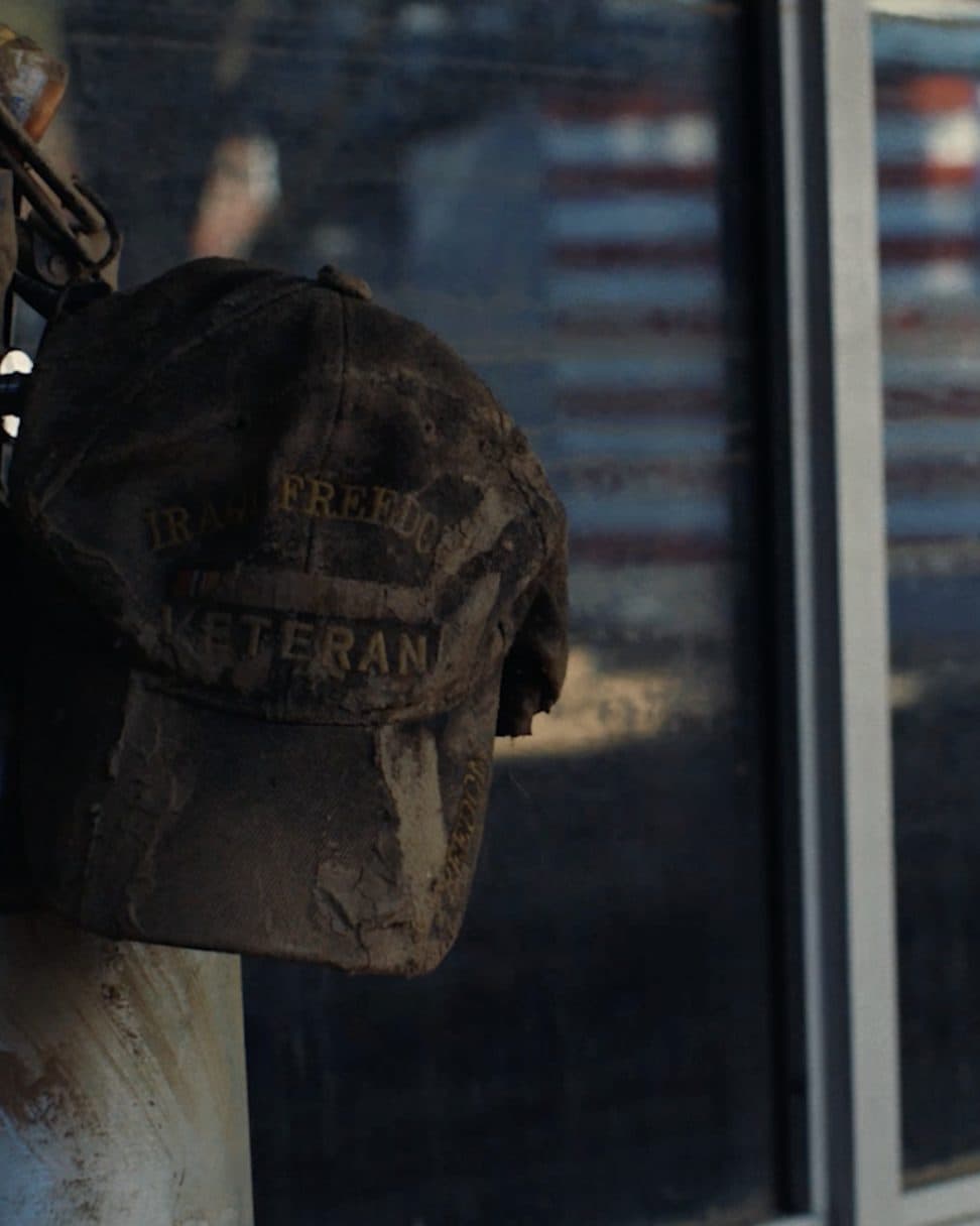 A helmet by a window with the American flag behind it.