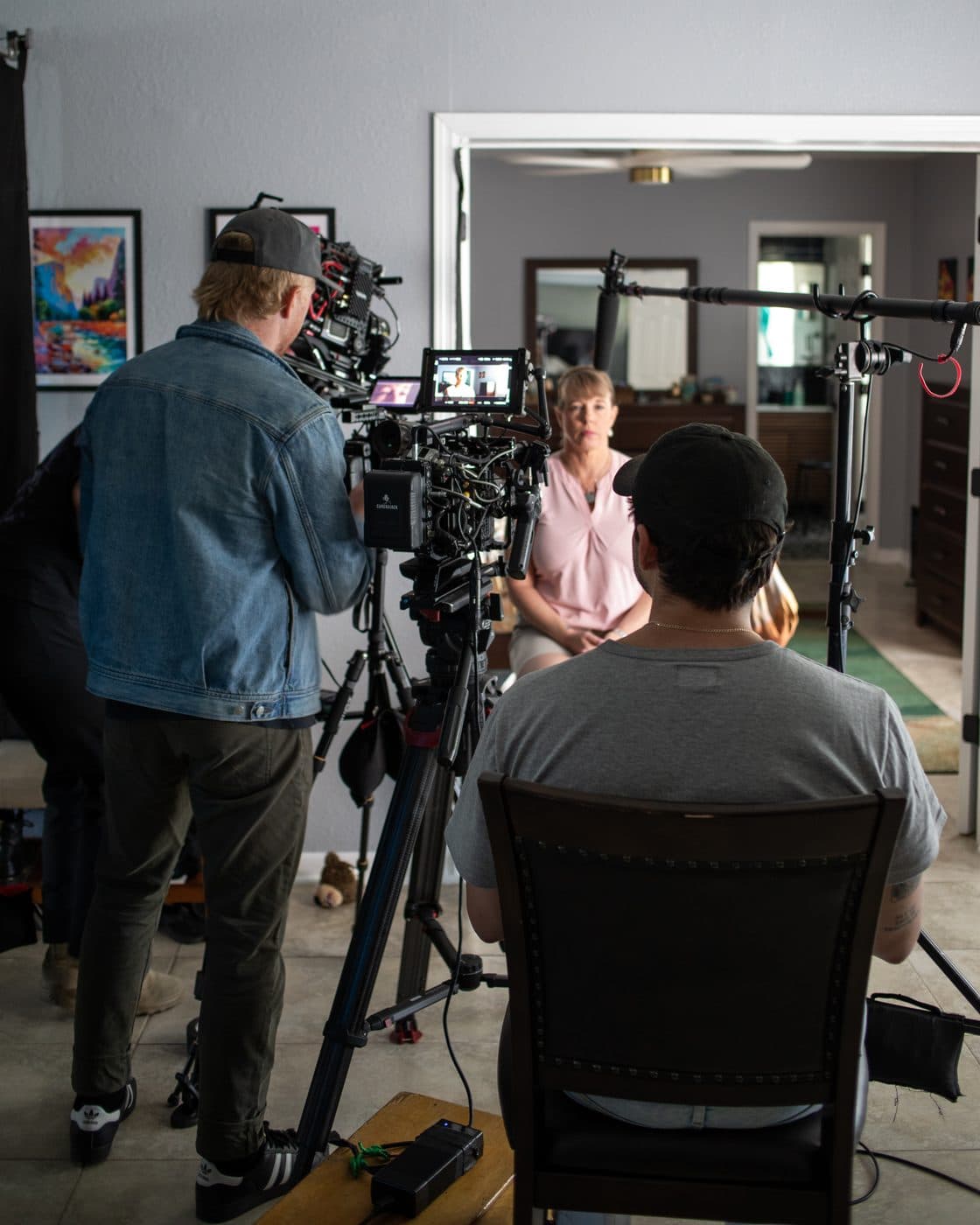 An interview set up in a living room, camera and lights on the subject.