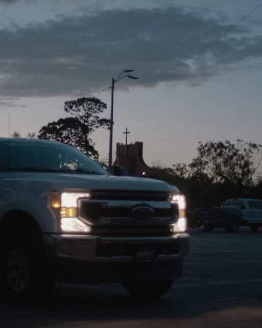 A Team Rubicon truck at dusk, headlights on.