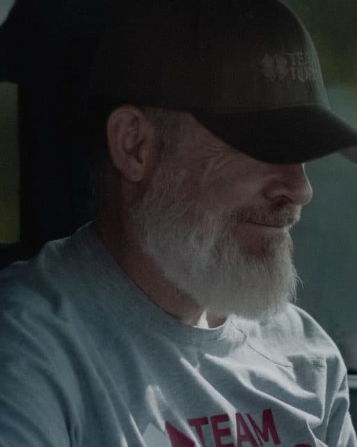 A Team Rubicon volunteer with a white beard, in his truck.
