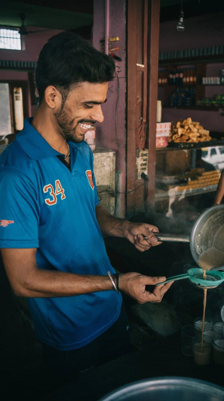 A man pouring tea in a market in India.