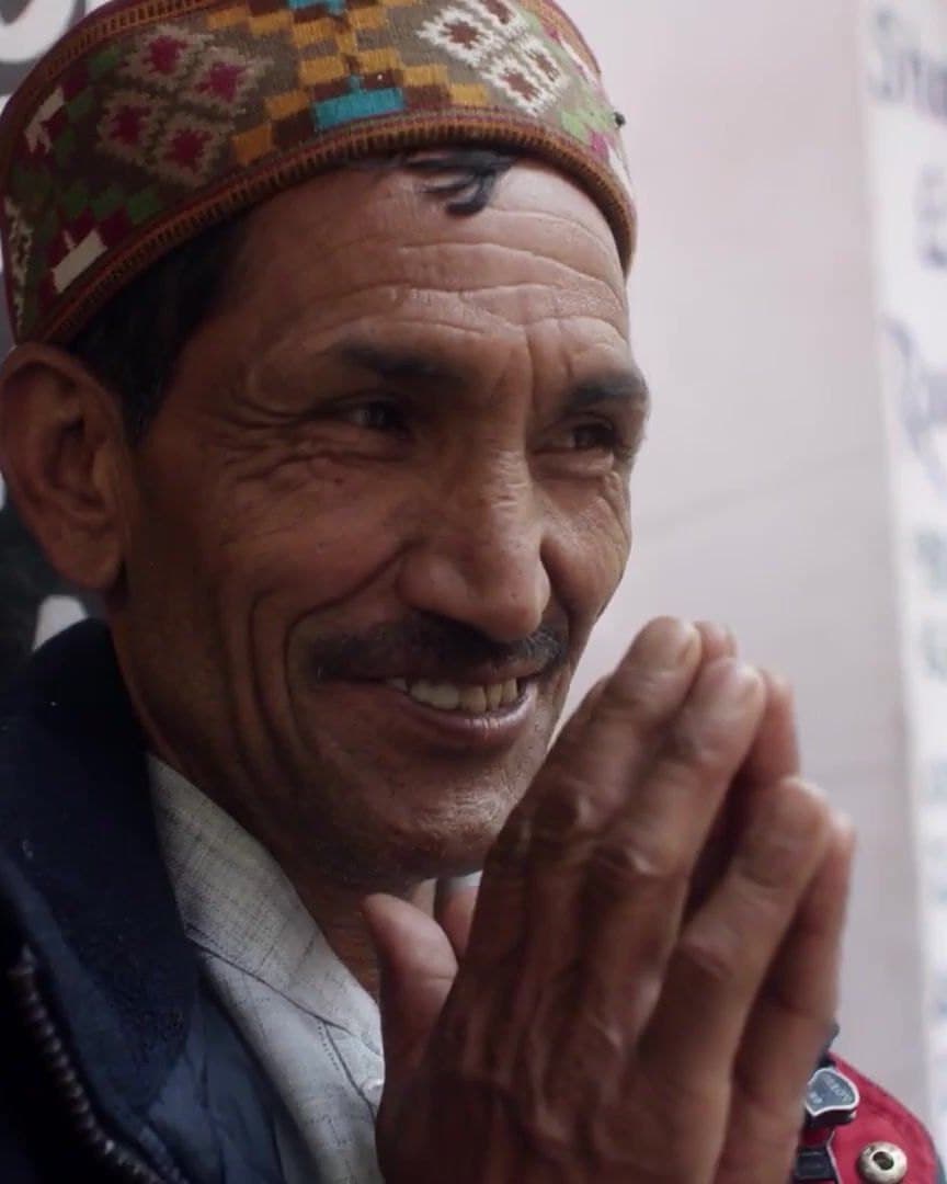 A man smiling with his hands pressed together, in India.