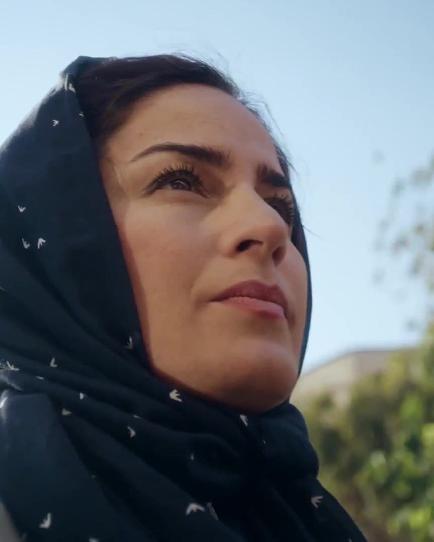 A woman in a headscarf looking up.