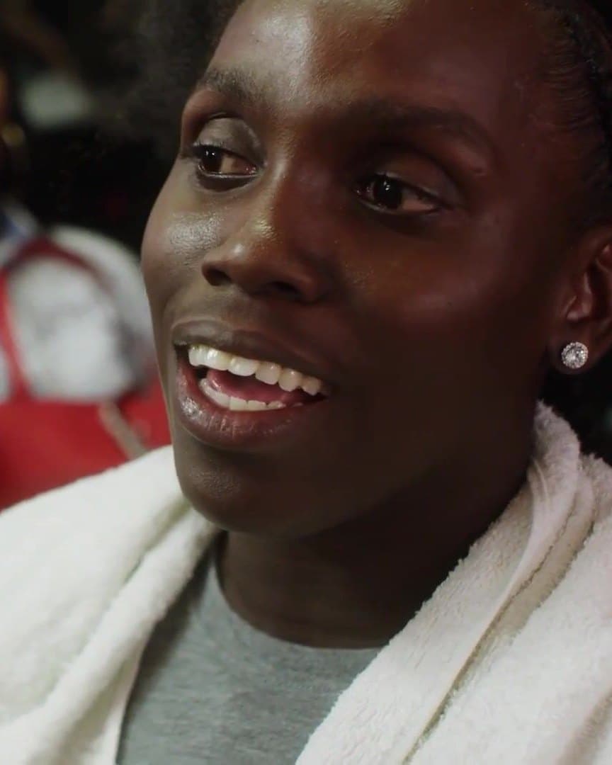 A bobsledder smiling, a towel around her neck.