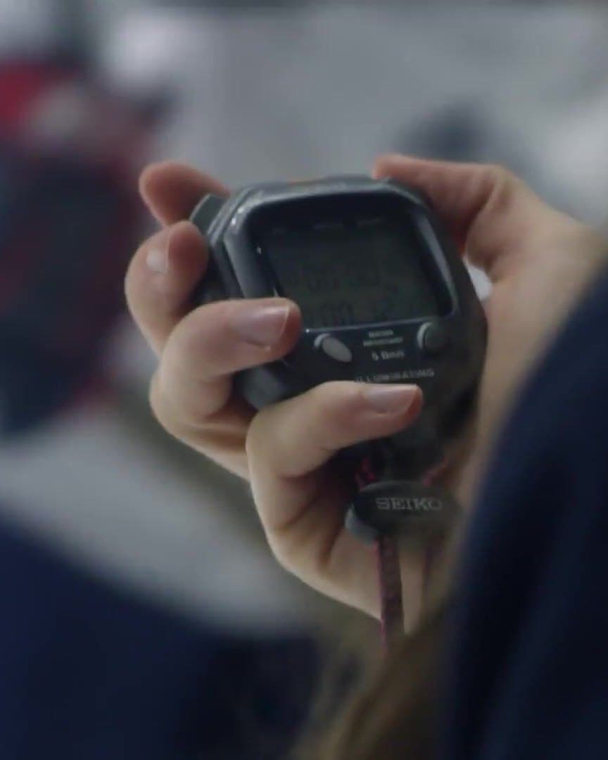 A coach’s hand on a stopwatch.