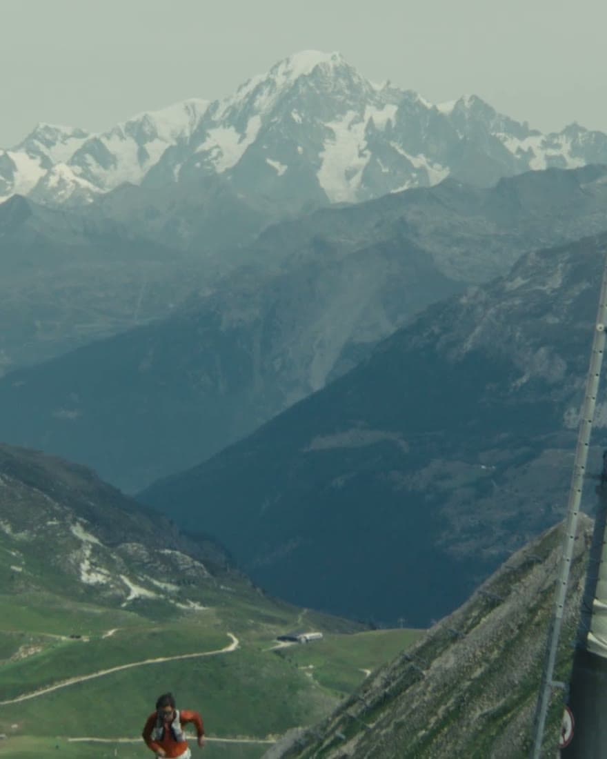 An alpine valley from high above, a village small on the floor of it.