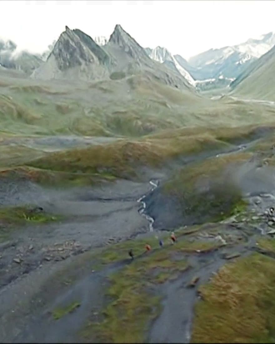 A rocky pass braided with meltwater streams under bare peaks.