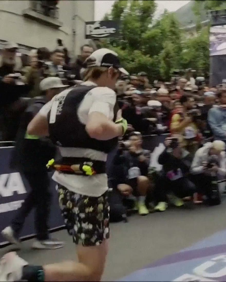 A runner coming through a dense crowd at the roadside.
