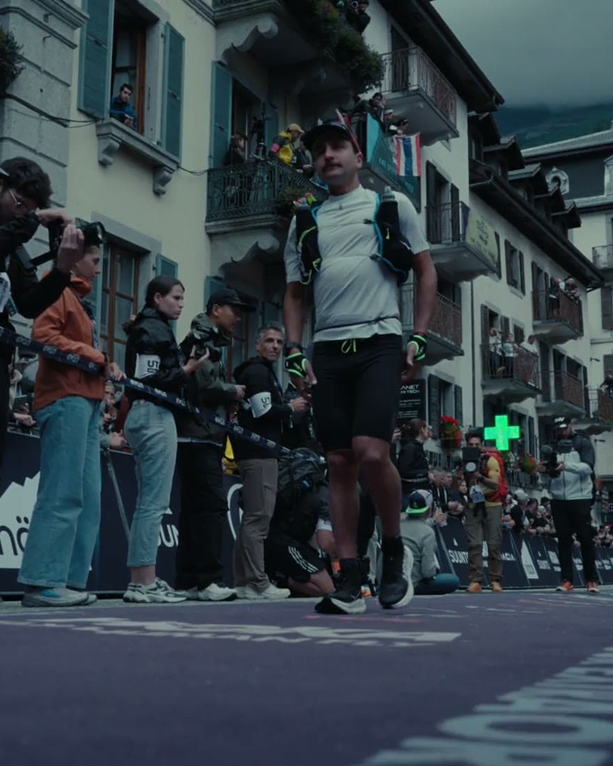 A runner passing spectators in a narrow alpine village street.