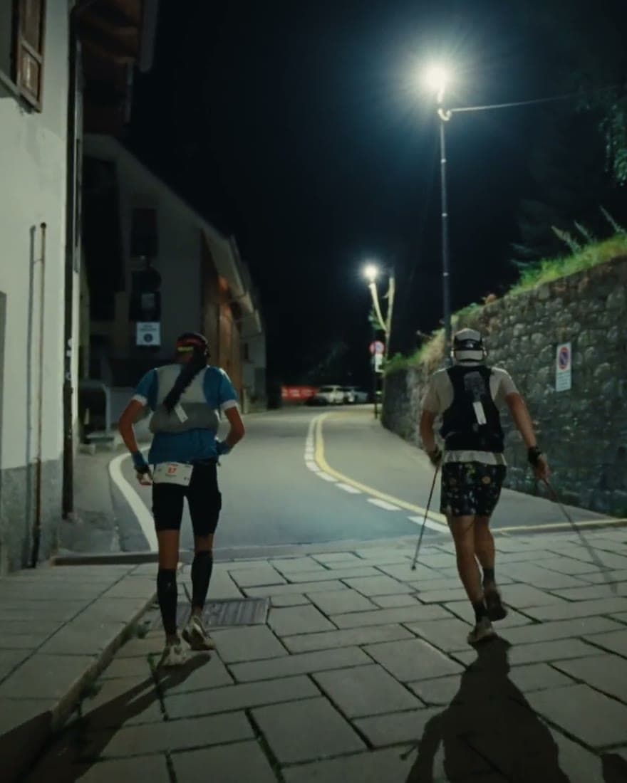 Two runners under streetlights on a village street at night.