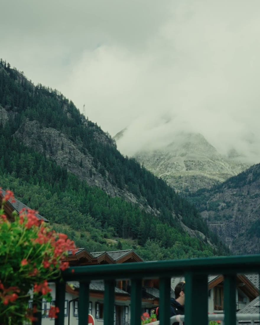 Flowers on a balcony rail, cloud coming down the valley behind.