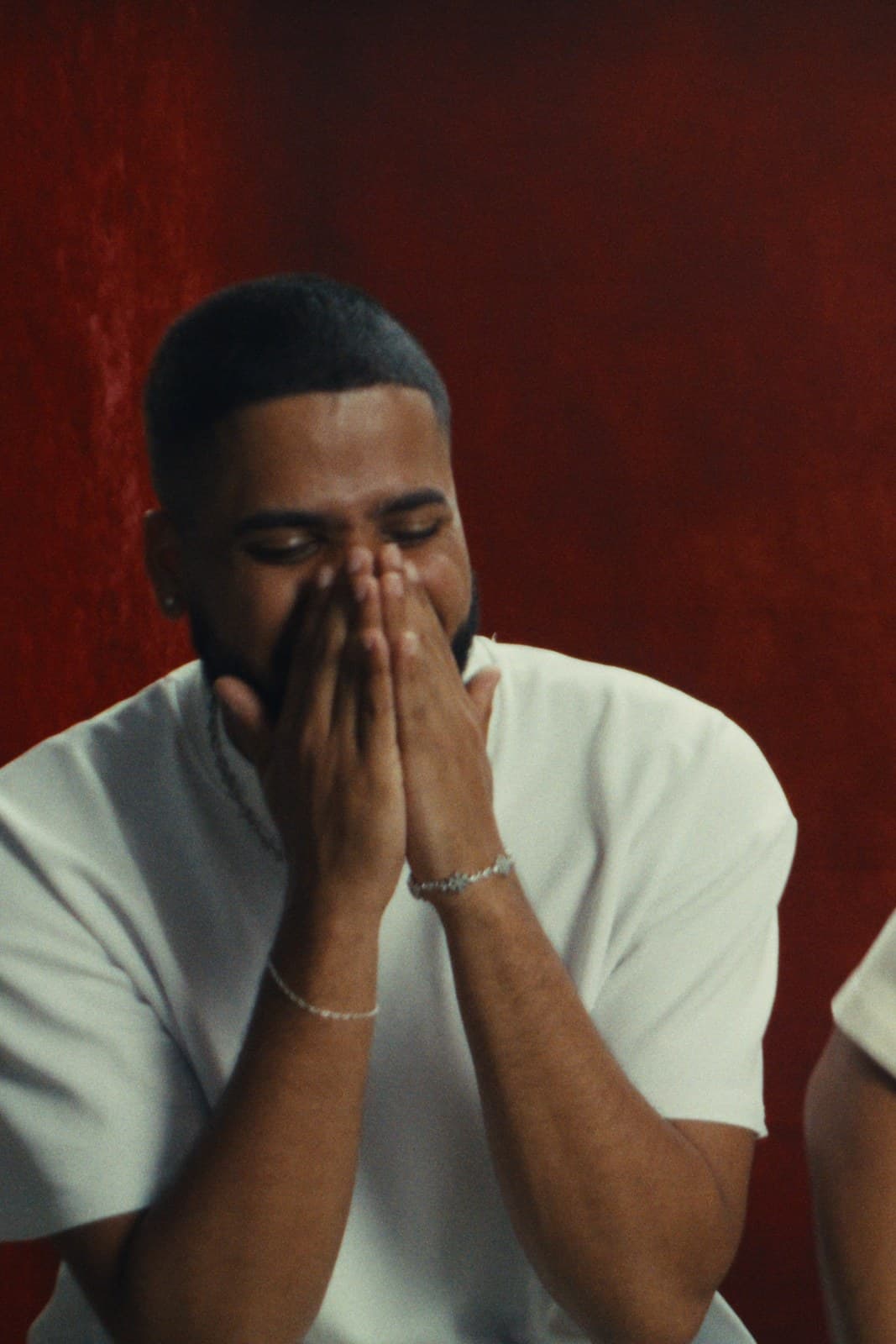 One of the twins laughing, hands over his face, in the interview.