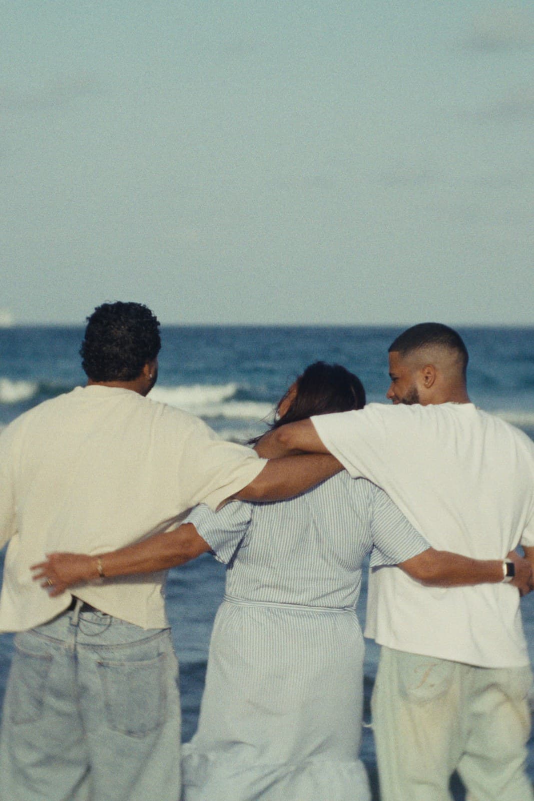 The twins walking arm in arm with their mother into the sea.
