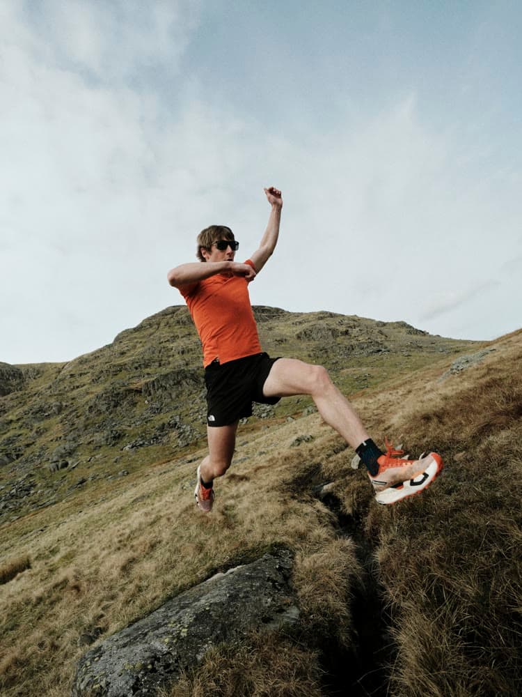 A runner leaping a gap on the open fell.