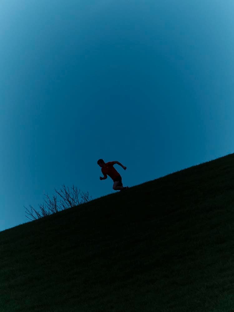 A runner silhouetted against a deep blue dusk sky.