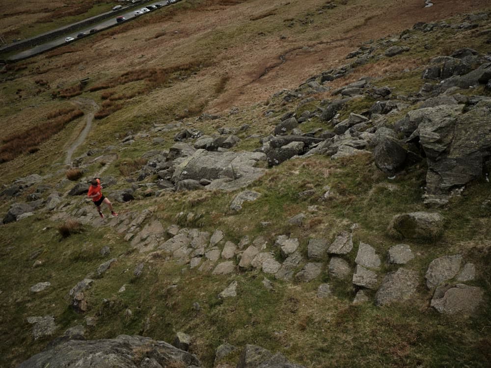 A runner small against a rocky slope, seen from above.