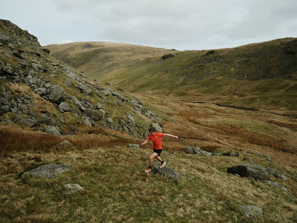 A runner crossing a broad hillside.