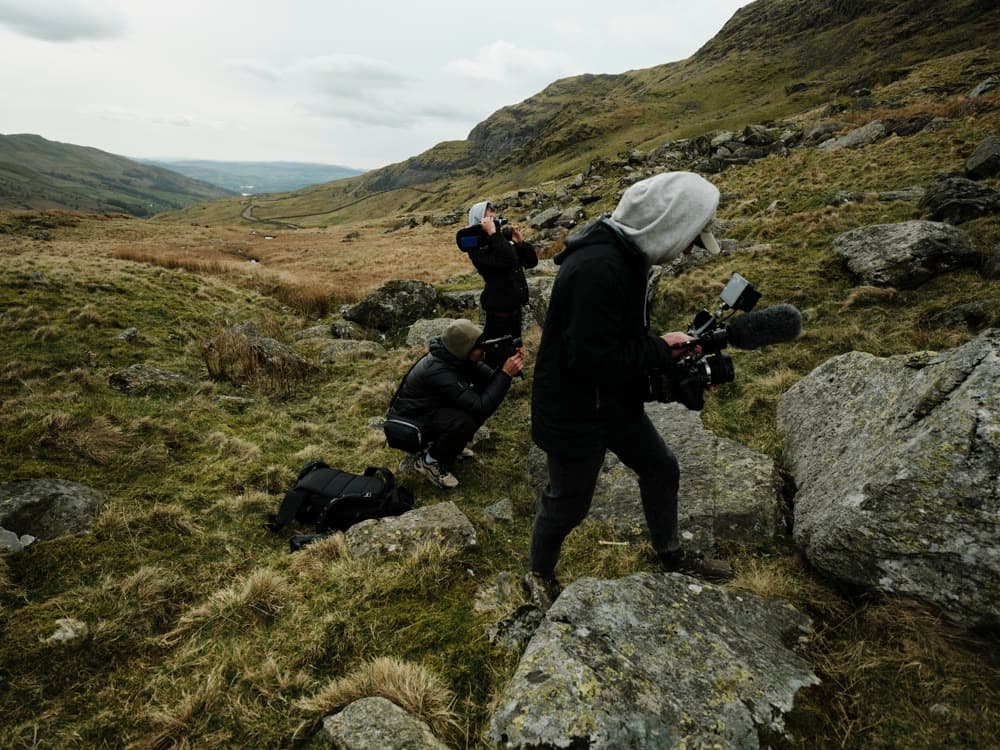 An operator filming a runner across broken ground.