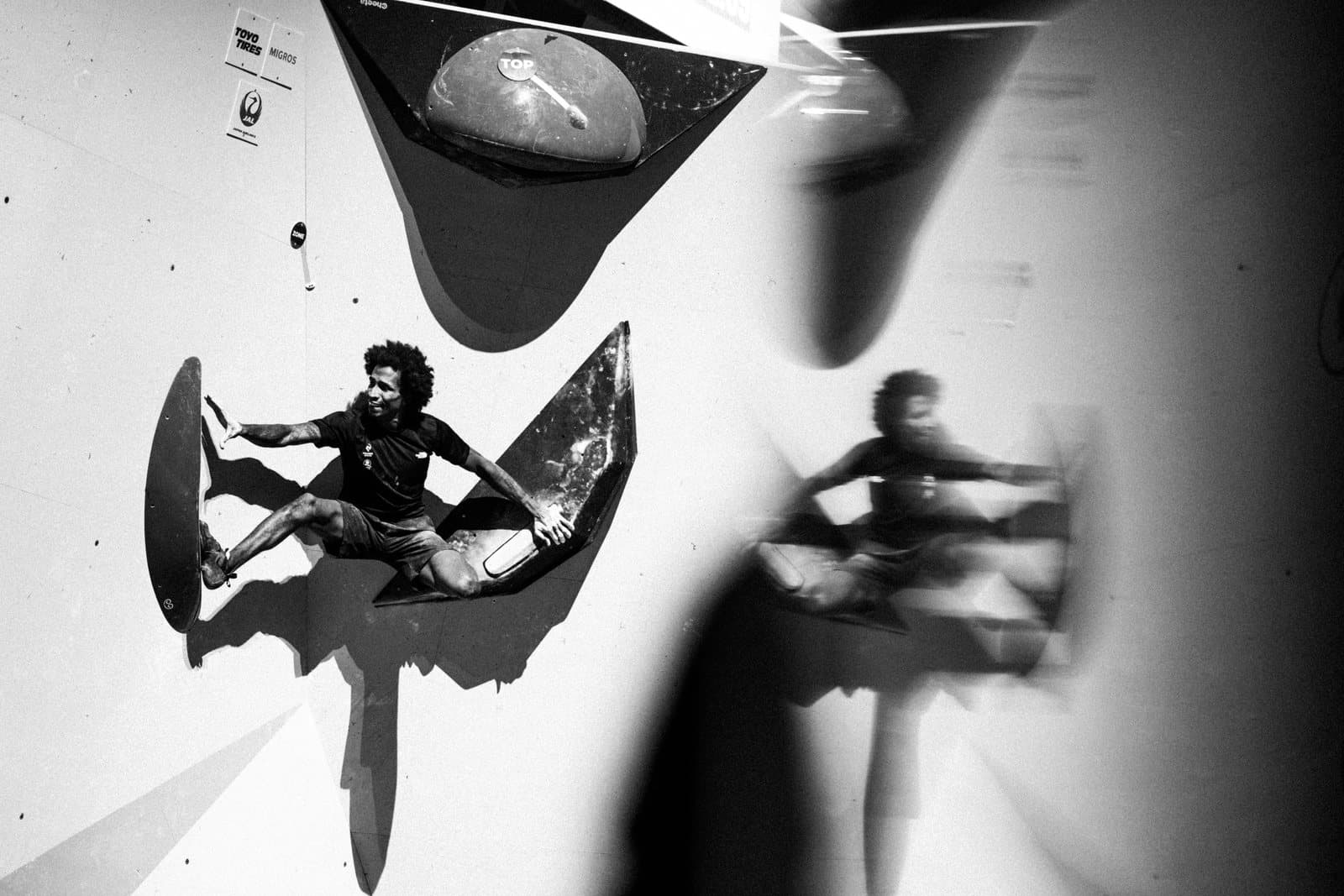 A climber on a dark volume, in black and white.