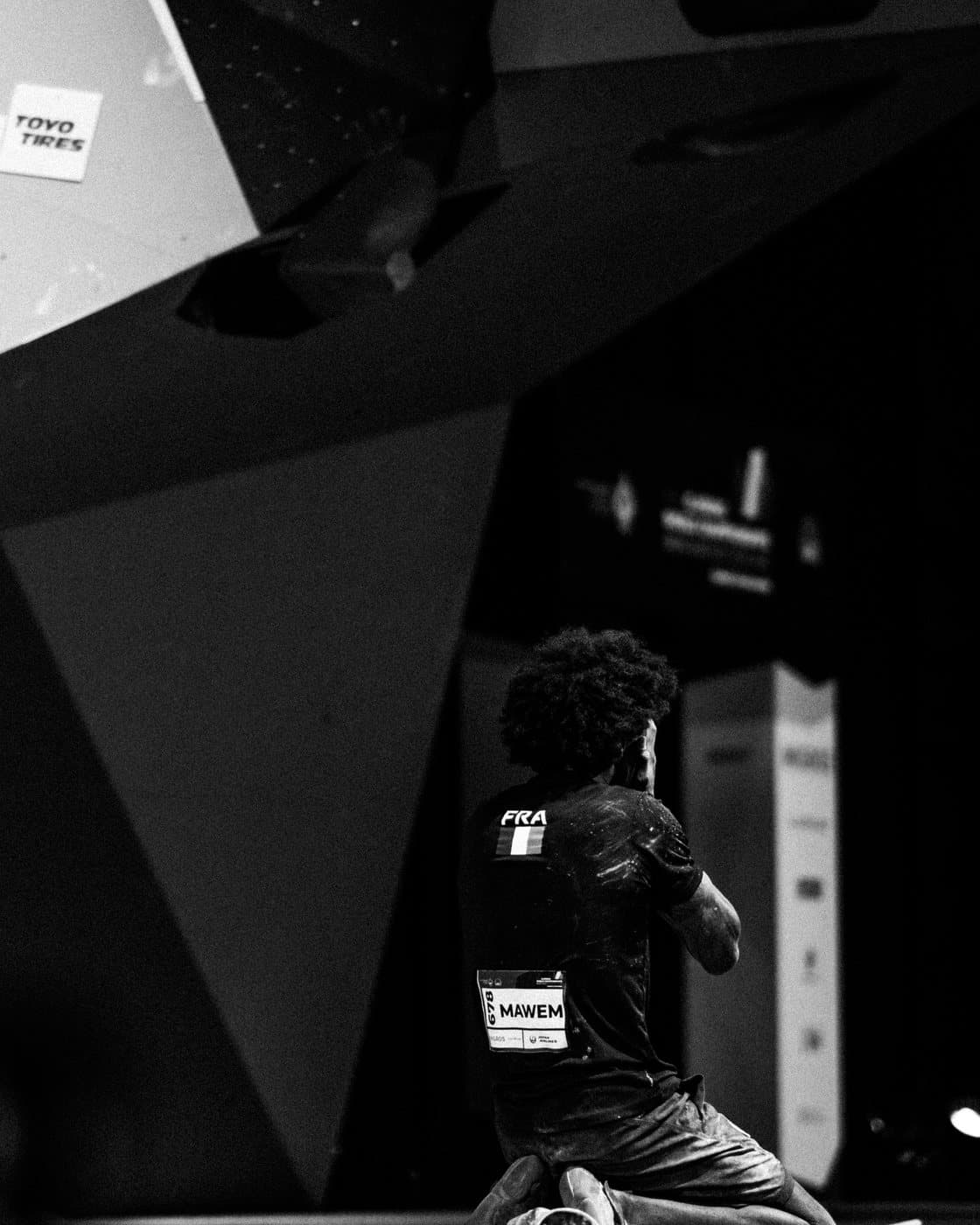 Backstage in black and white, a climber waiting in the dark.