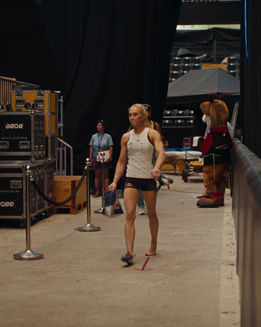 A climber walking backstage past road cases.