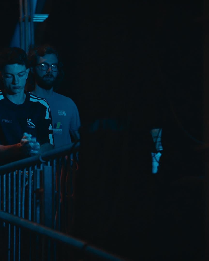 Athletes waiting in the dark behind the barriers.