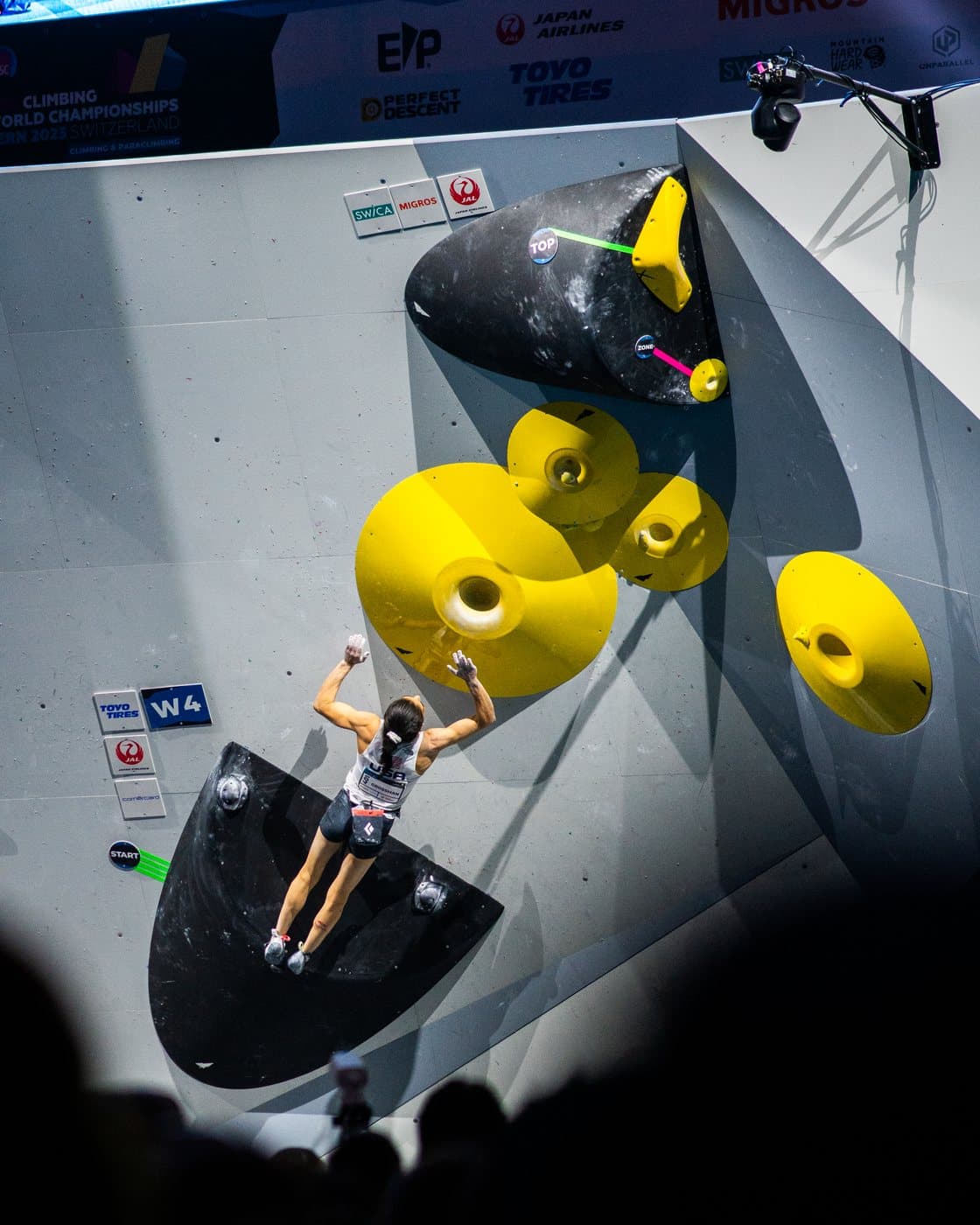 A climber on a yellow volume above the crowd.