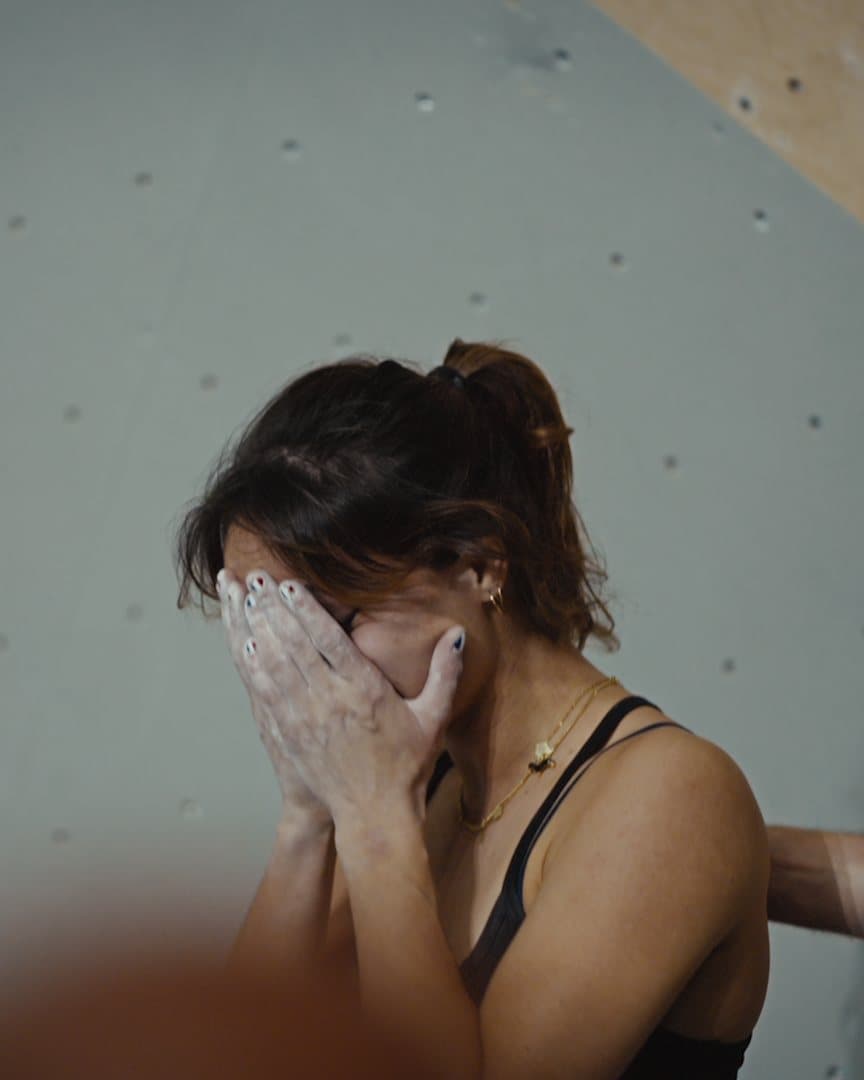 A climber with her hands over her face.