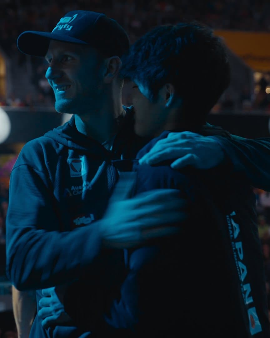 Two athletes hugging in front of the crowd.