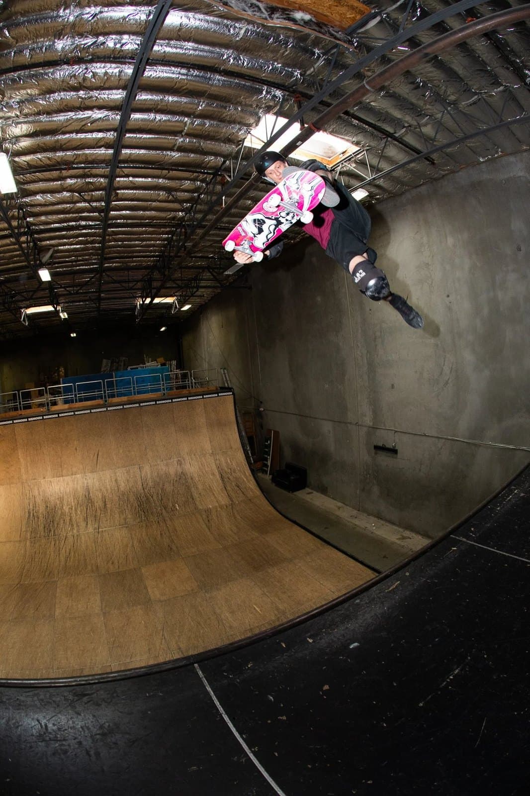 Tony Hawk in the air over the halfpipe in his warehouse.