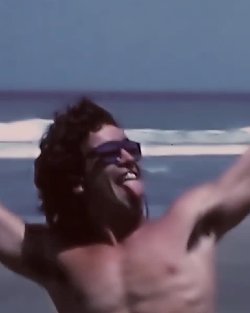 A surfer celebrating on the beach, from the archive.