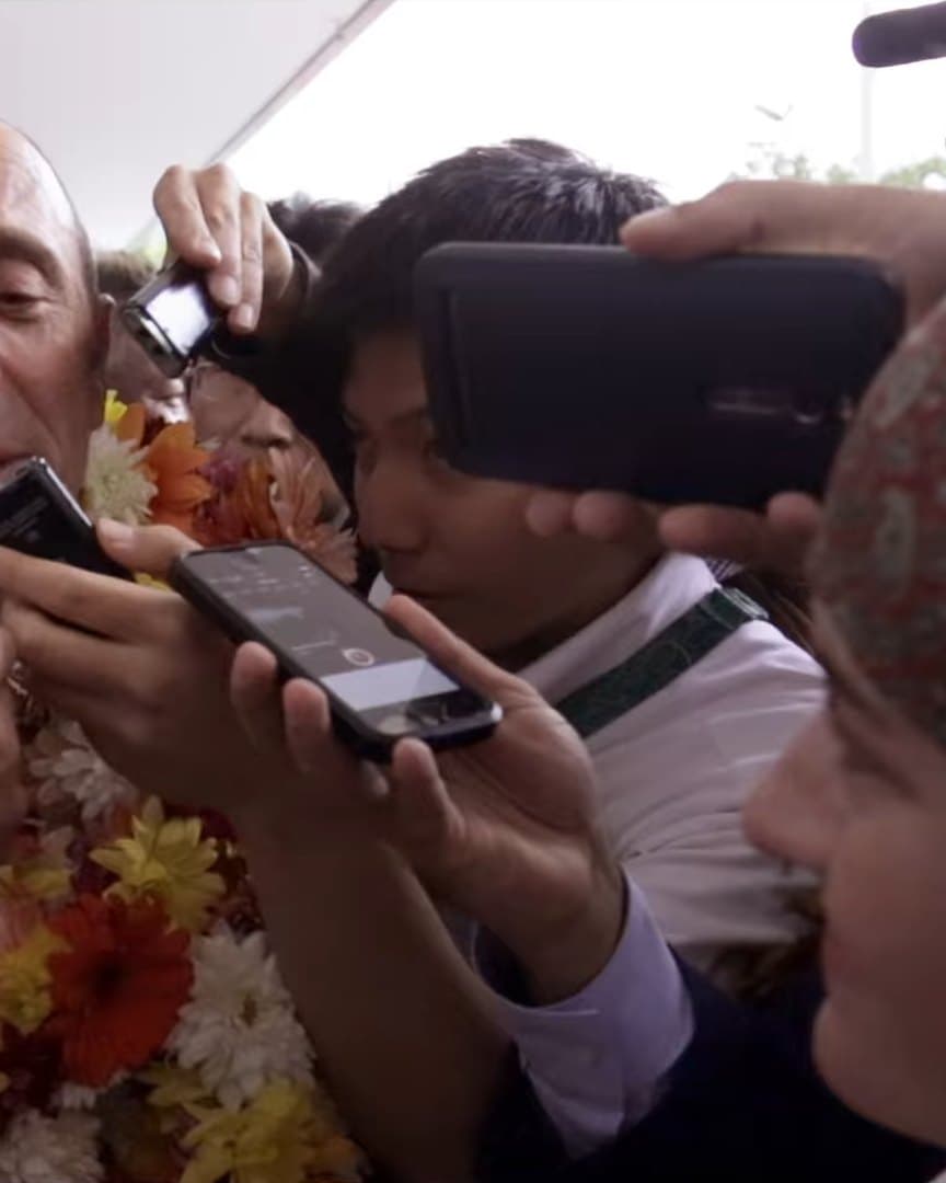 Reporters crowding an official with phones and microphones.