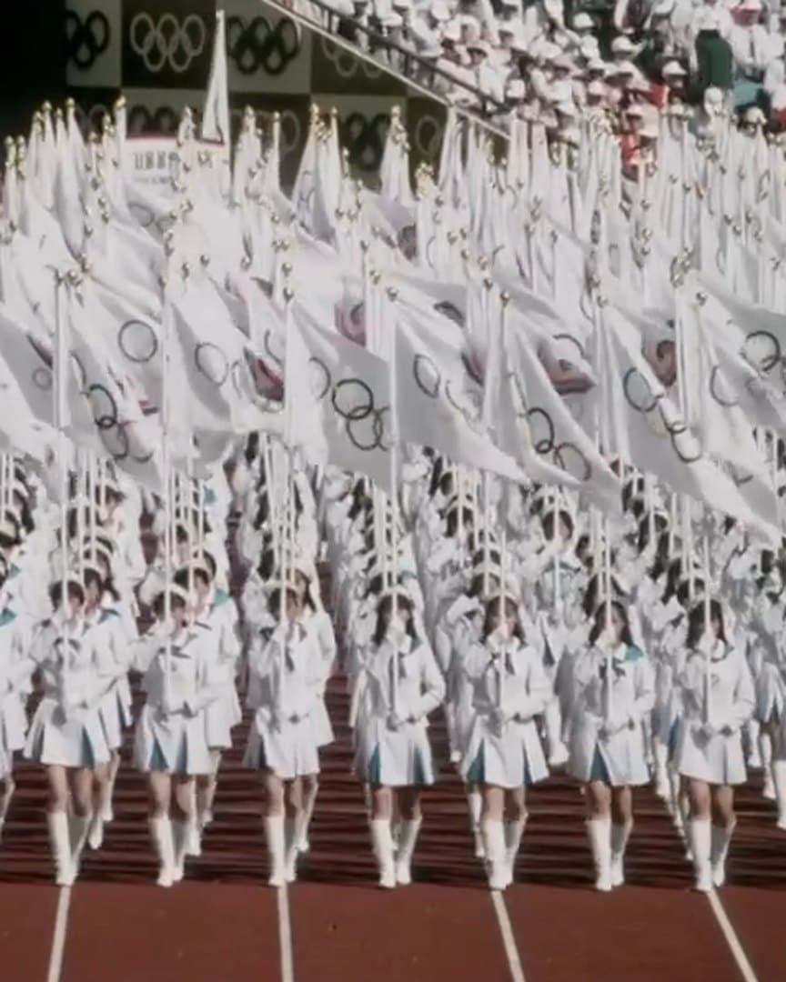 Performers in white at an opening ceremony, from the archive.