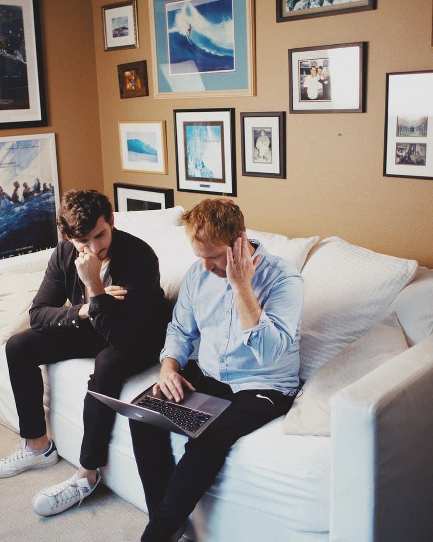 Two officials reading on a sofa during an interview set-up.